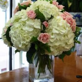 White hydrangea bouquet with pink roses in a clear glass vase