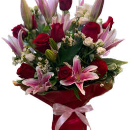 Bouquet of red roses and pink lilies wrapped in red paper