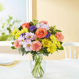 Mixed bouquet of roses, daisies, and carnations in a glass vase