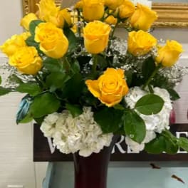 Yellow roses and white hydrangeas in a tall vase