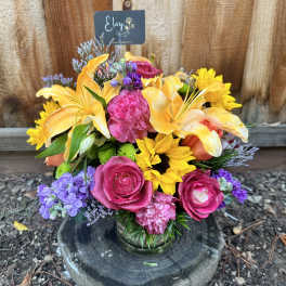 Colorful mixed bouquet in a glass vase with roses, lilies, and sunflowers