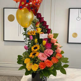 Tall bouquet of multicolored roses with balloons in a black vase