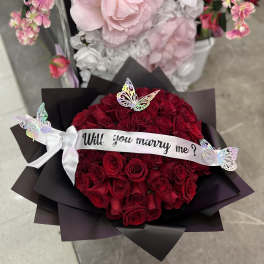 Bouquet of red roses with a "Will you marry me?" ribbon and butterflies