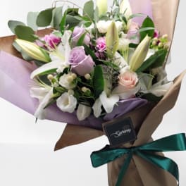 Bouquet of white lilies and pastel roses wrapped in brown paper