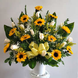 Large bouquet of yellow sunflowers and white roses in a white container