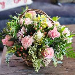 Pink roses and carnations in a wicker basket