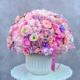 Large pink and lavender bouquet in a white vase with a ribbon