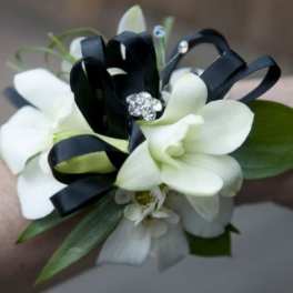 White orchid wrist corsage with black ribbon and rhinestone accents