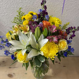 Mixed bouquet of lilies, roses, and bright flowers in a glass vase