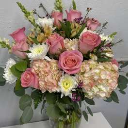 Pink roses and mixed blooms arranged in a clear glass vase