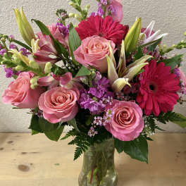 Pink roses and hot pink gerbera daisies in a clear glass vase
