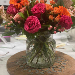 Bright mixed bouquet of pink roses and orange gerbera daisies in a glass vase