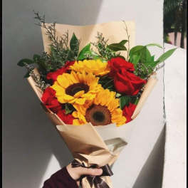 Bouquet of red roses and yellow sunflowers wrapped in beige paper
