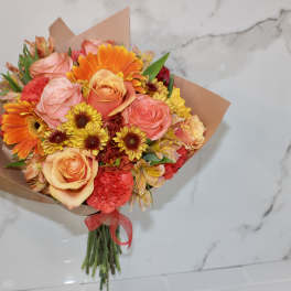 Bouquet of orange, pink, and yellow flowers wrapped in brown paper