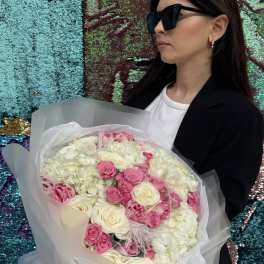 Woman holding a bouquet of pink and white flowers wrapped in translucent paper