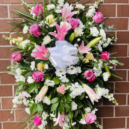 Pink and white floral standing spray with a white bow