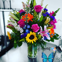 Mixed bouquet of roses, lilies, and sunflowers in a glass vase