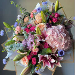 Large bouquet of pink lilies, roses, hydrangea, and blue accent flowers