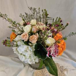 Mixed bouquet of roses, hydrangeas, and carnations in a glass vase