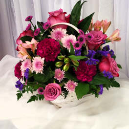 Basket arrangement of pink roses, carnations, and purple daisies