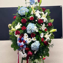 Standing floral spray with red roses, white lilies, and blue hydrangeas