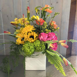 Bright mixed bouquet in a white square vase with sunflowers and pink roses