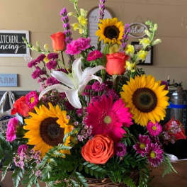 Basket arrangement with sunflowers, roses, lilies, and pink mixed blooms