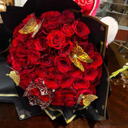 Bouquet of red roses wrapped in black paper with gold butterfly accents