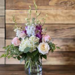 Pink and white roses with purple orchids in a glass vase