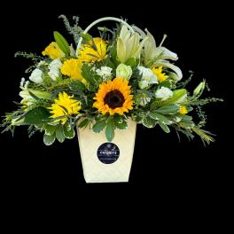 Yellow and white mixed flower arrangement in a cream container