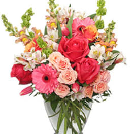 Mixed bouquet of pink and red flowers in a clear glass vase