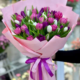 Bouquet of pink, purple, and white tulips wrapped in pink paper