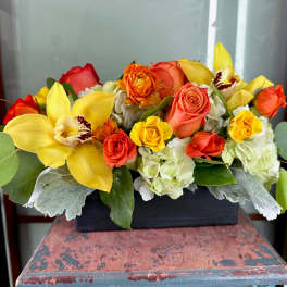 Yellow orchids and orange roses in a black rectangular container