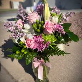 Pink and white mixed bouquet in a glass vase with a pink ribbon