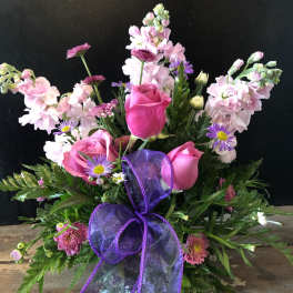 Pink roses and purple flowers arranged with a purple ribbon