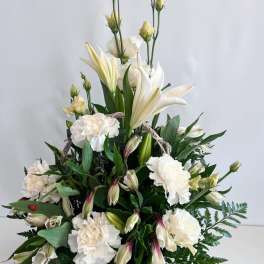 White lilies and carnations arranged in a basket with greenery