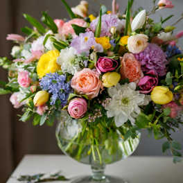 Mixed pastel flower arrangement in a glass pedestal vase