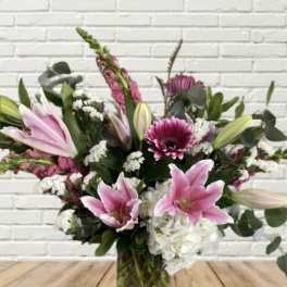 Pink lilies and mixed flowers arranged in a glass vase