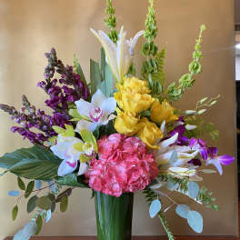 Mixed bouquet with hydrangea, orchids, roses, and lilies in a glass vase