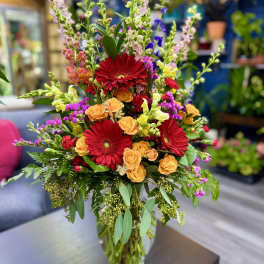 Mixed bouquet with red gerbera daisies and orange roses in a glass vase