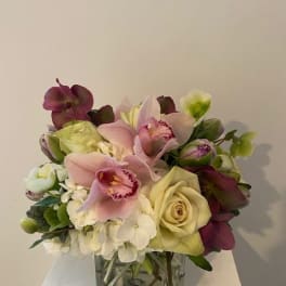 Bouquet of pink orchids and cream roses in a square glass vase