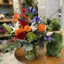 Mixed bouquet of roses, lilies, and purple flowers in a glass vase