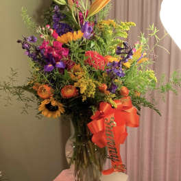 Colorful mixed bouquet in a glass vase with a red ribbon