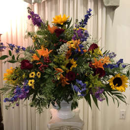 Large mixed flower arrangement in a white urn