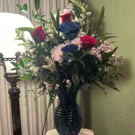 Mixed bouquet of roses and daisies in a dark vase