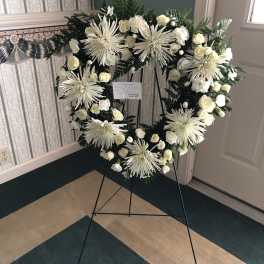 White floral wreath on a black easel stand