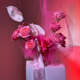 Pink rose arrangement with white anthuriums and a ribbon on a pedestal