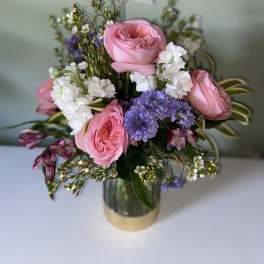 Pink roses and purple flowers arranged in a metallic vase
