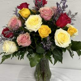 Mixed roses in pink, red, yellow, and white in a glass vase