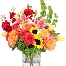 Mixed bouquet of roses, lilies, sunflowers, and tulips in a glass vase